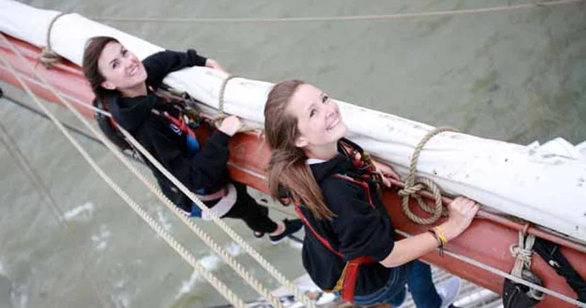 Two women on a sail boat smiling for the camera during Tall Ships Regatta in Falmouth.