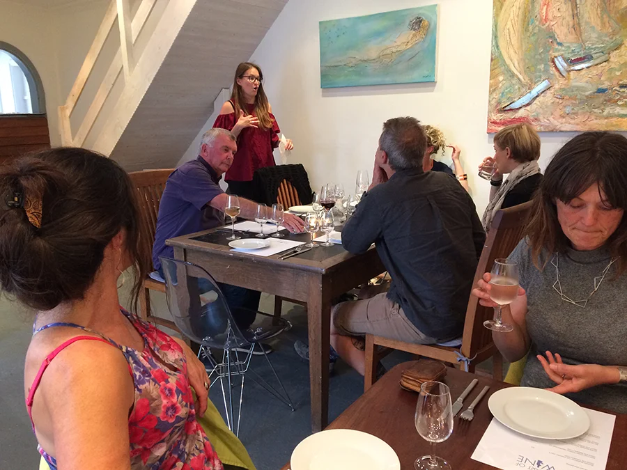 A group of adults enjoying a wine tasting evening as the host talks to them all.