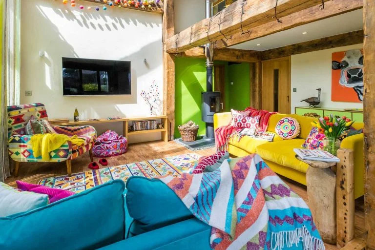 A country style living room with exposed wooden beams and bright soft furnishings