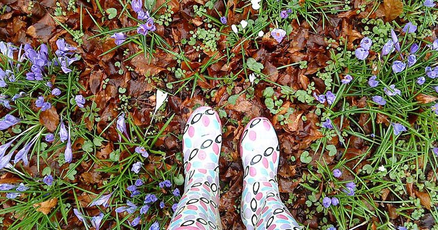 Point of view shot of a person looking down at their floral wellies whilst stood amongst leaves and flowers at Bosinver
