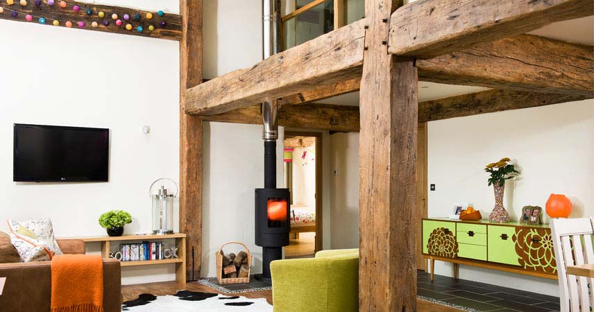 Indoor of an eco house at Bosinver in Cornwall, showing a cosy interior with TV, seating and fireplace.