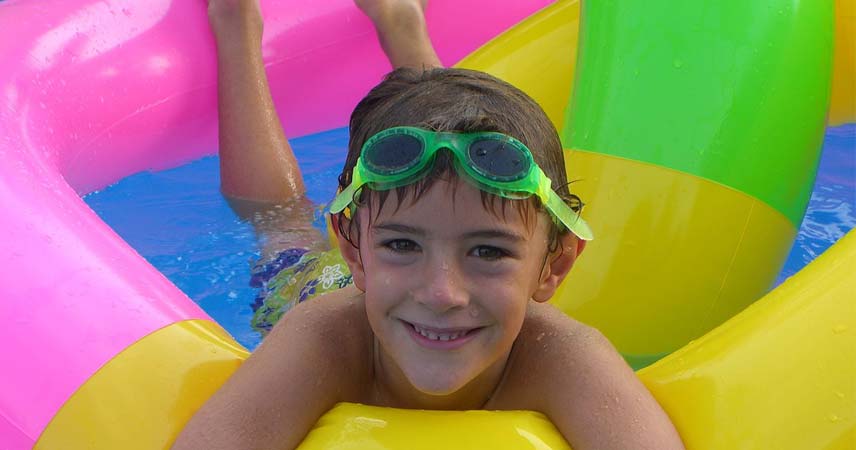 Boy using an inflatable ring in a swimming pool with goggles on his forehead at Bosinver