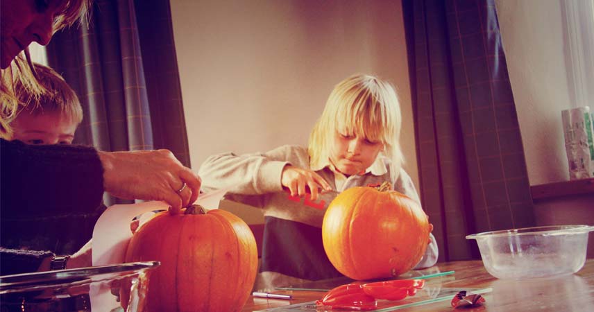 Child sitting at a table to carve a pumpkin