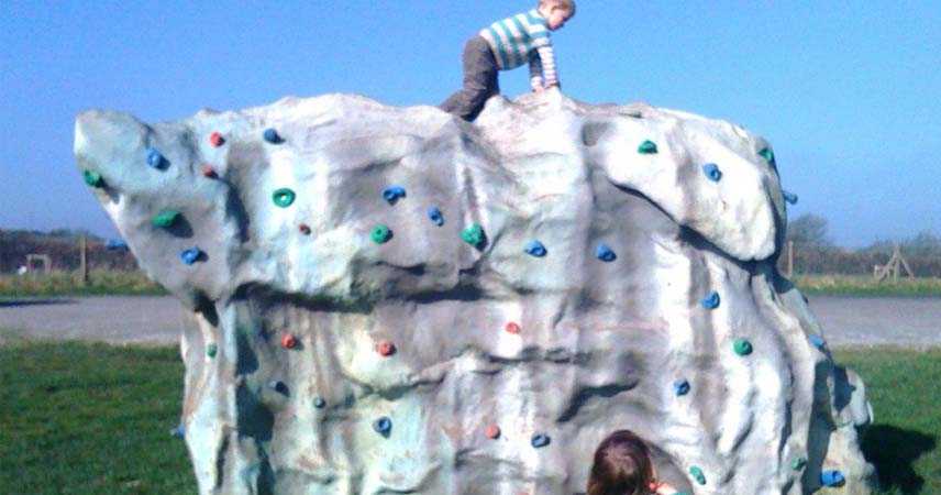Young child playing outside on a white outdoor rock climbing frame
