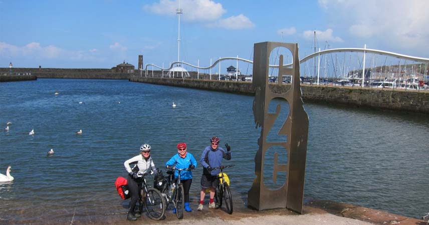 Ground of 3 cyclists posing in front of a bridge
