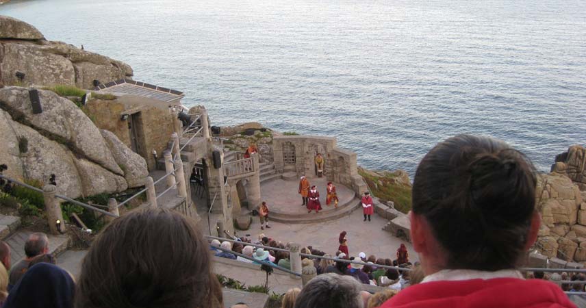 Actors performing at the outdoor Minack Theatre in Cornwall whilst an audience watches