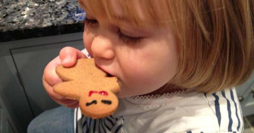Child eating a gingerbread man after baking with Pat at Bosinver.