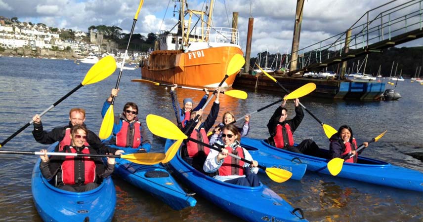 Group posing for the camera whilst in kayaks in Cornwall