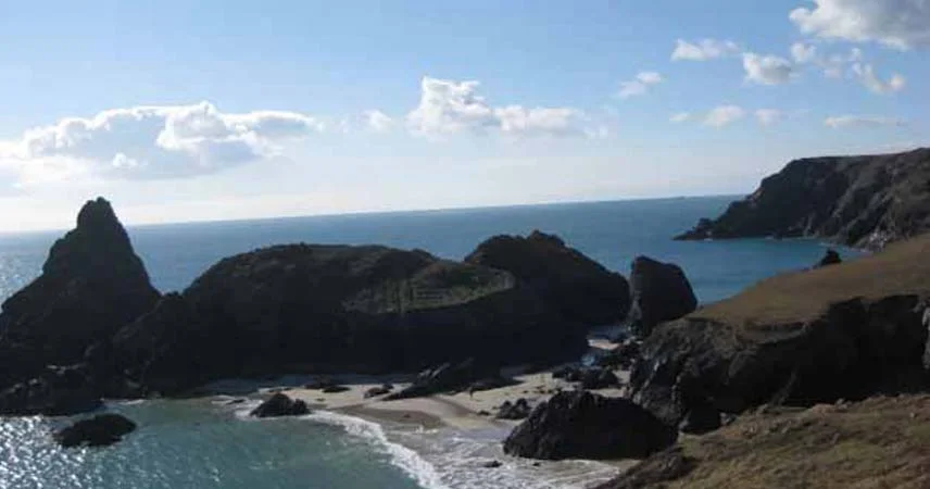 Aerial shot of Kynance Cove in Cornwall. The sea is calm and it's a sunny day.