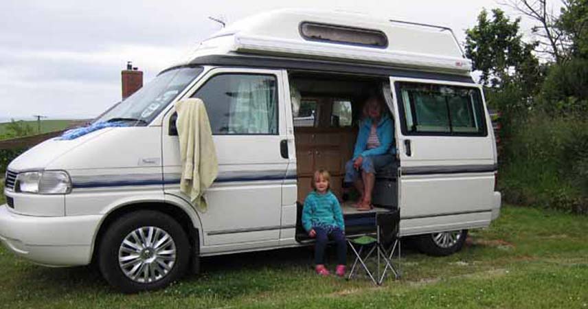 Pat and a child sitting in a campervan on the Roseland Peninsula on a grey day.