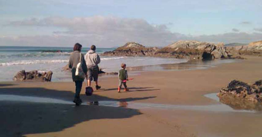 Three people walking along the beach on the Rame Peninsula in Cornwall
