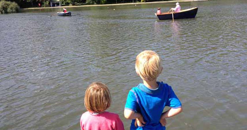 Two children watching the boats row by at Helston Boating Lake in Cornwall.