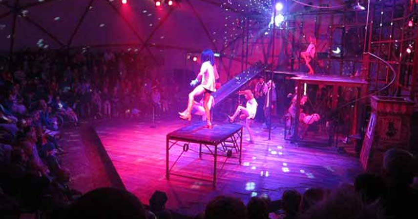Photo from a performance from Kneehigh Theatre in Cornwall under pink/purple lights.