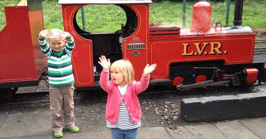 Two children posing for the camera next to a train at Lappa Valley in Cornwall
