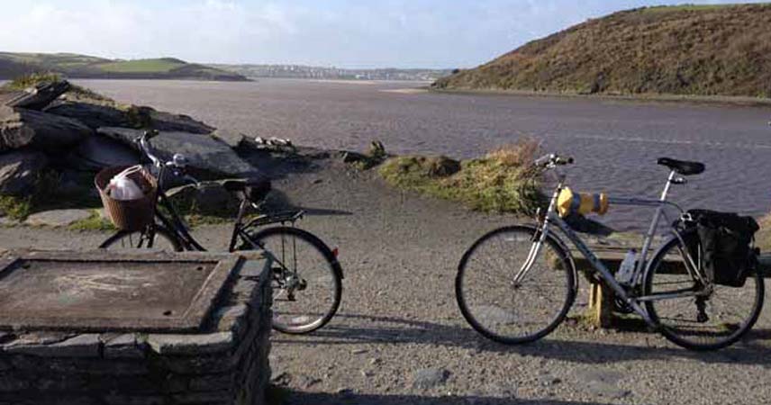 Two bikes on a cycle trail by a river in Cornwall.