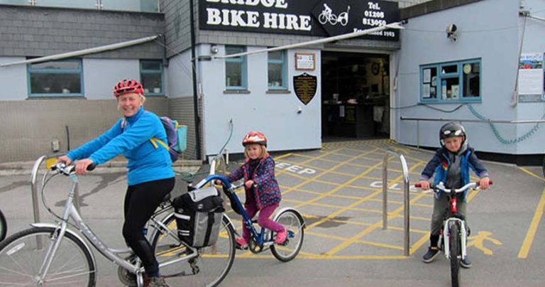 Three people with bikes and helmets rented from Padstow Bike Hire.