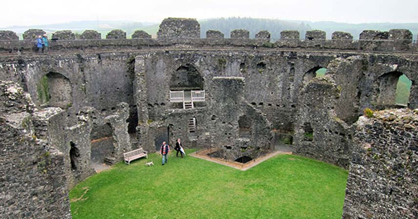 Aerial shot of the inside of Restormel Castle with two adults walking around in the middle of it.