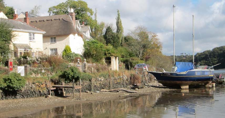 Boat moored up by a house with a thatched roof at Tresillian