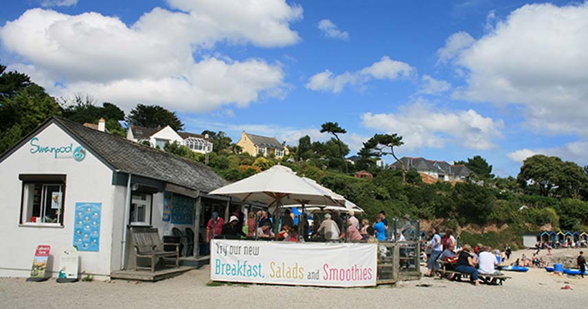 Picture of a cafe on Swanpool beach in Cornwall, serving breakfasts, salads and smoothies. The cafe is full of people.
