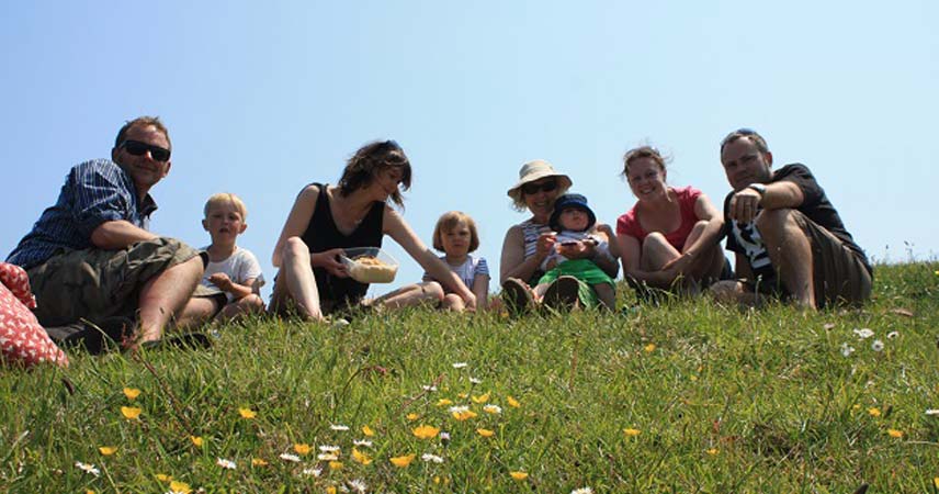 Large family group eating a picnic in a field in Cornwall