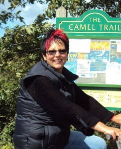 Tracey Findlow smiling on a bike infront of the Camel Trail notice board after her weightloss journey