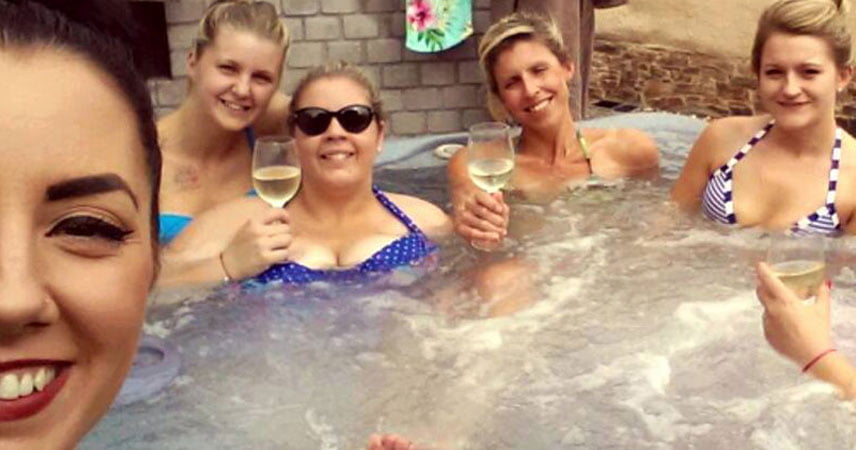 Six women relaxing in a jacuzzi at Bosinver drinking wine.