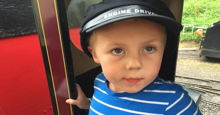 Small boy dressed as an engine driver on a train at Lappa Valley.