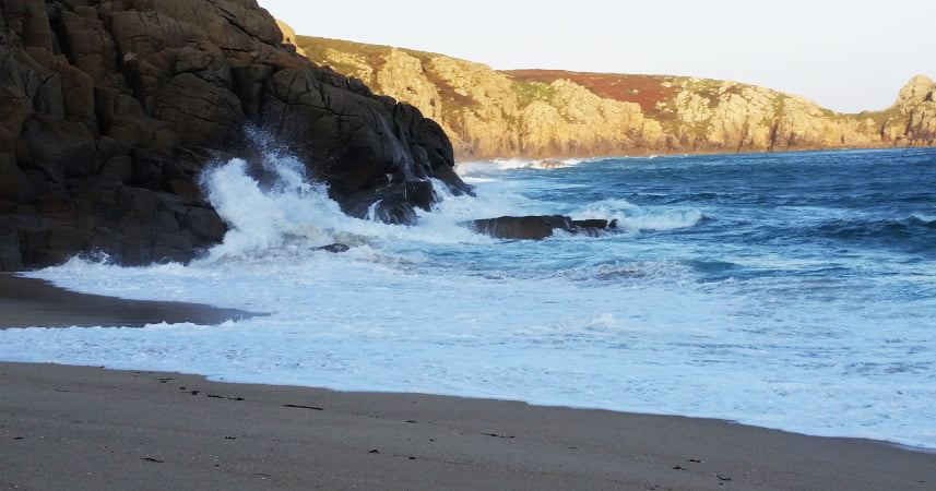 Picture of Porthcurno beach in Cornwall, with waves crashing against the rocks.