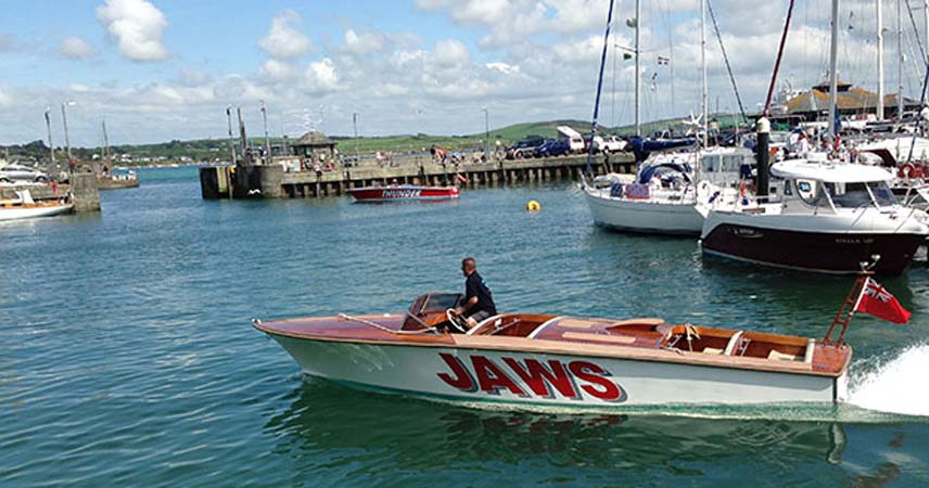 Speedboat leaving the harbour at Padstow with other boats moored up.