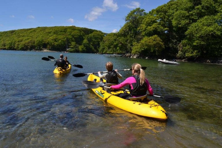Four people canoeing around Cornwall on a sunny day