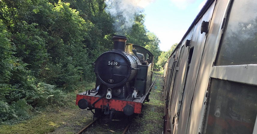 Steam train moving down the track at Bodmin and Wenford Railway