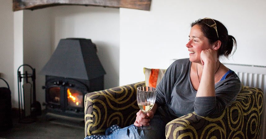 Woman smiling drinking wine by the fire at Bosinver.