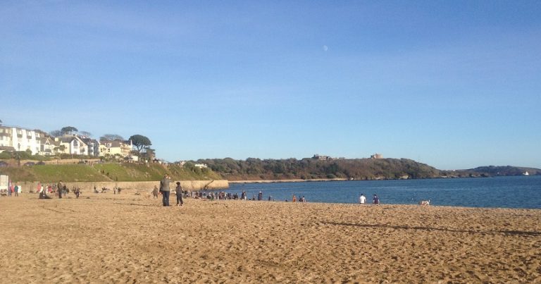Group of people on Falmouth beach on a sunny winter day.