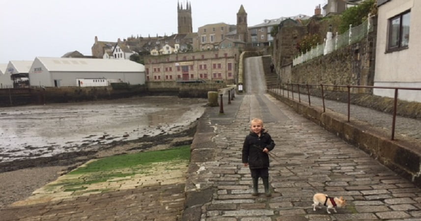 Child holding a dog with Penzance in Cornwall in the background.