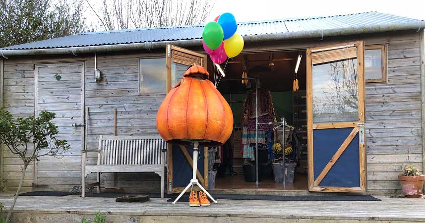 Pumpkin costume on a stand outside a wooden building