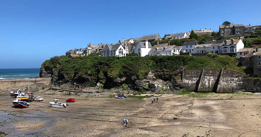 Landscape shot of Port Isaac Harbour at low tide and cottages on the cliff side