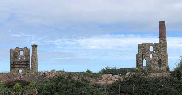 landscape shot of two old tin mine chimneys and walks of building