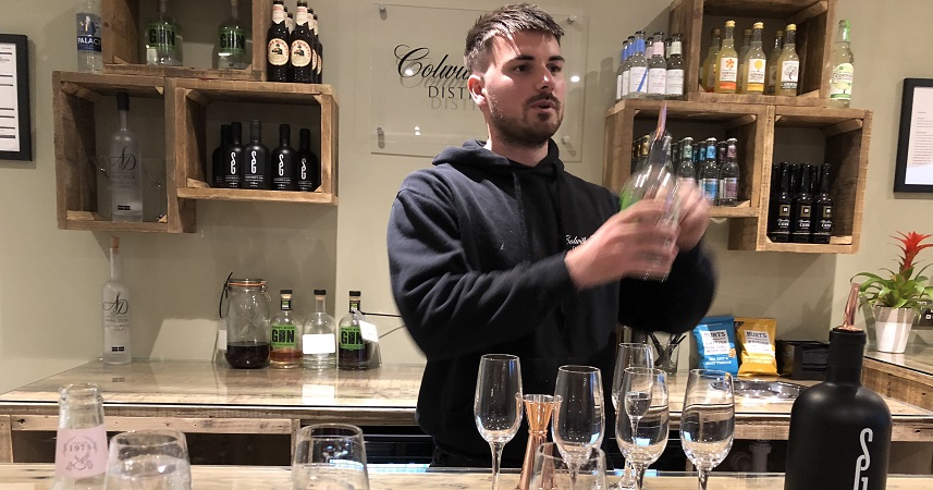 Barman in black hoodie holding a bottle of gin