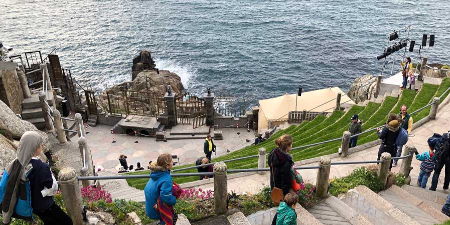 Group of people and families walking down the cliff to the outdoor cornwall theatr The Minack