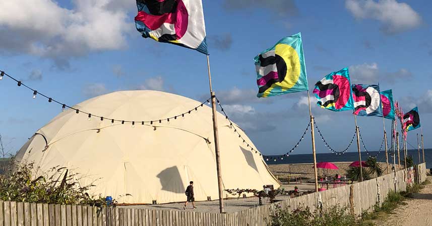 Large dome stage tent on cornish beach with festival flags