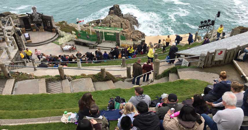 Aerial shot of the outdoor theatre in Cornwall with a large audience sitting on the cliff side