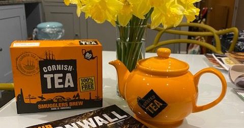 Cornish tea bags box, a Cornish tea branded tea pot, daffodils and an Our Cornwall magazine on a white table