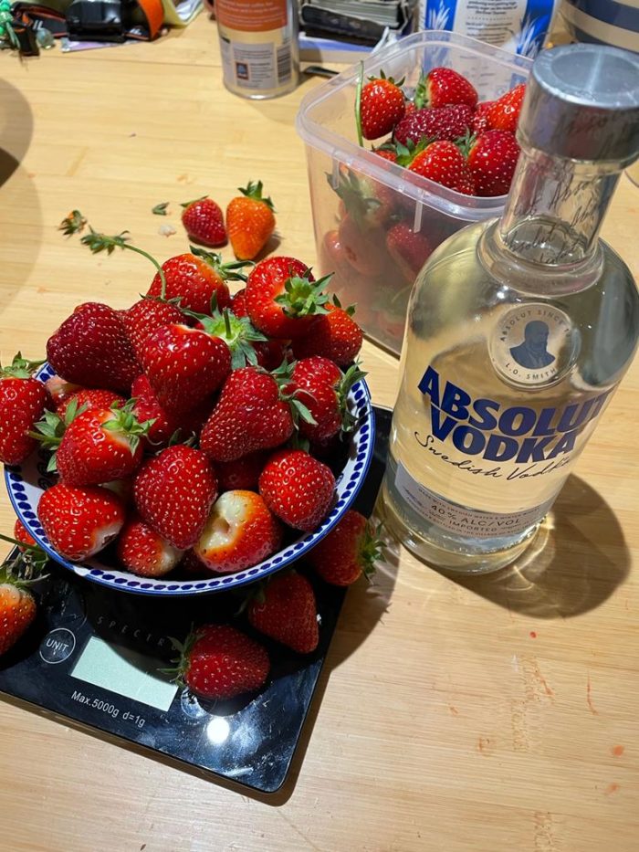 Strawberries next to a vodka bottle for strawberry liqueur