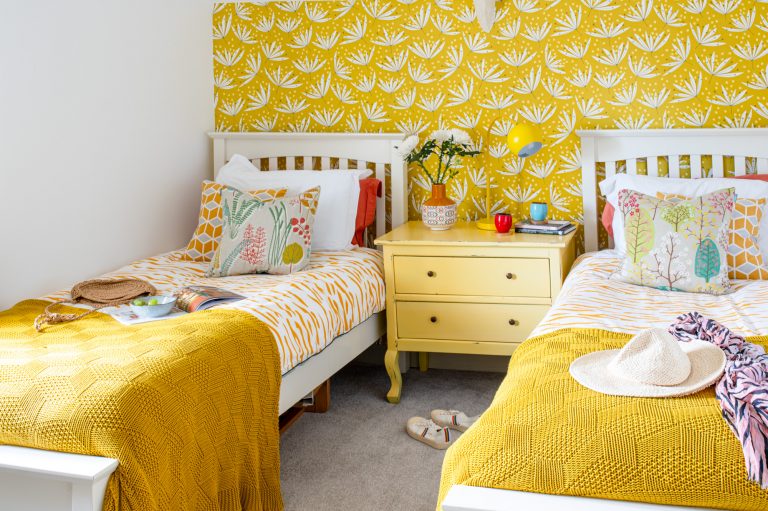 Twin bedorom for children decorated with yellow feature wall and coordinating bed spreads