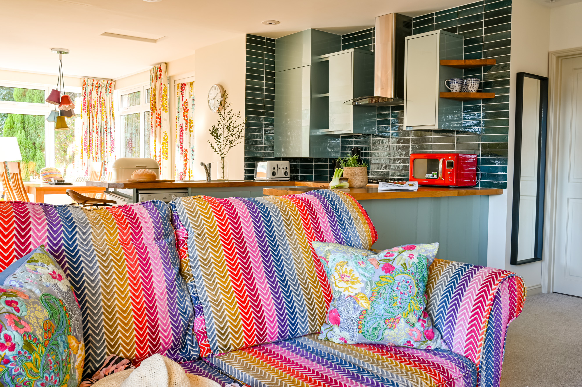 Open plan living space showing corner of sofa looking over to the kitchen