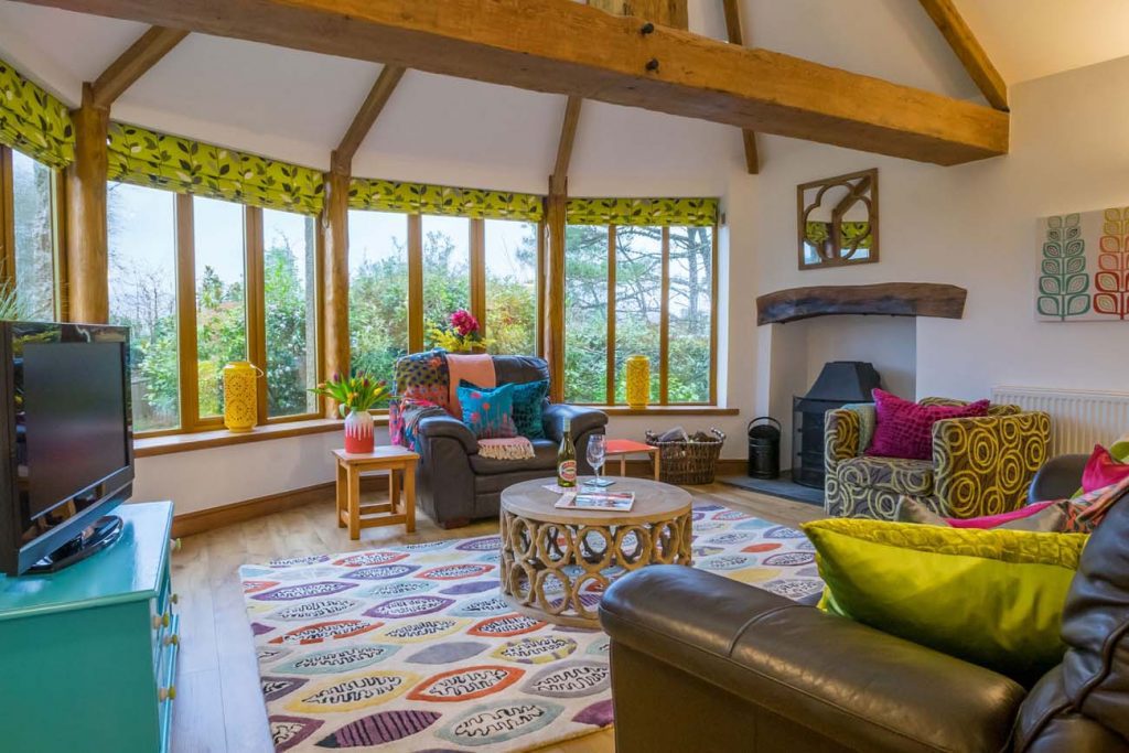 Interior of a holiday cottage in Cornwall, showing a cosy living room with sofa, armchair, coffee table and fire place.