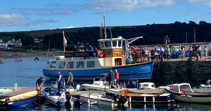 Boats in the harbour at St Mawes, with people boarding the boats ready to set sail