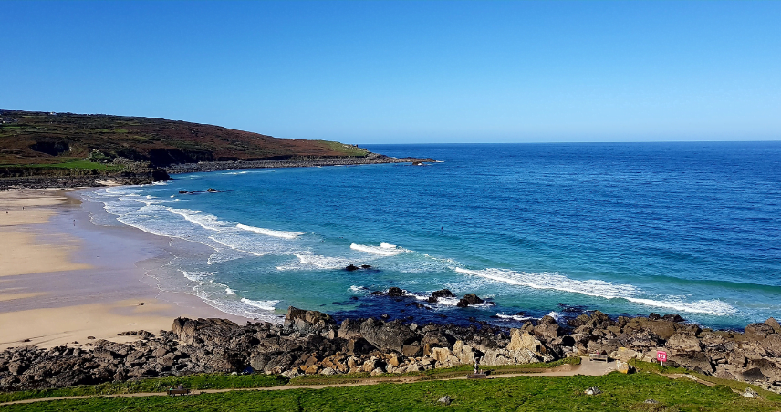 A wide shot of a Cornwall beach on a sunny day.