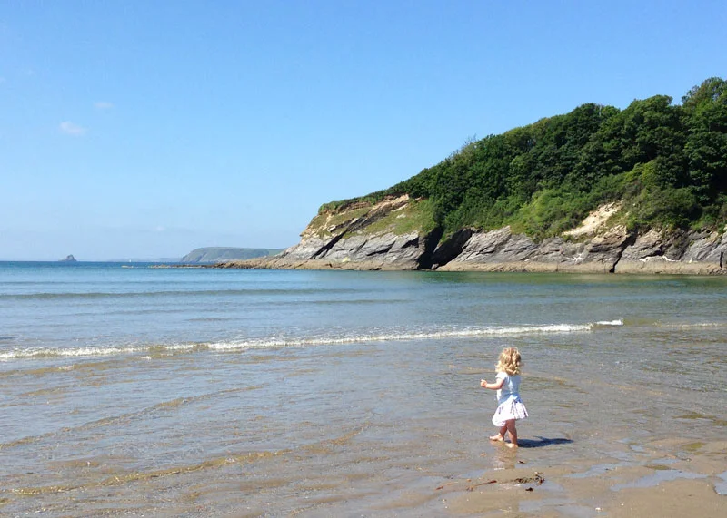 A little girl paddling at the waters edge