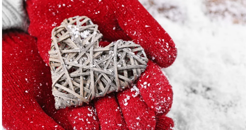 A close up of a wicker heart being held by red gloves hands